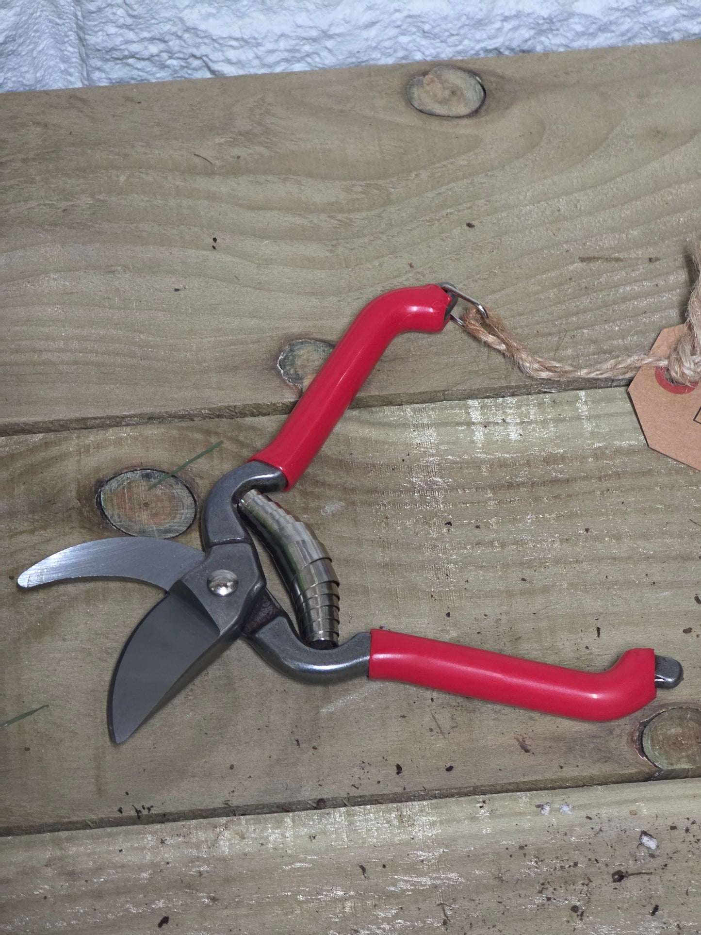 Red bypass pruners on a wooden table