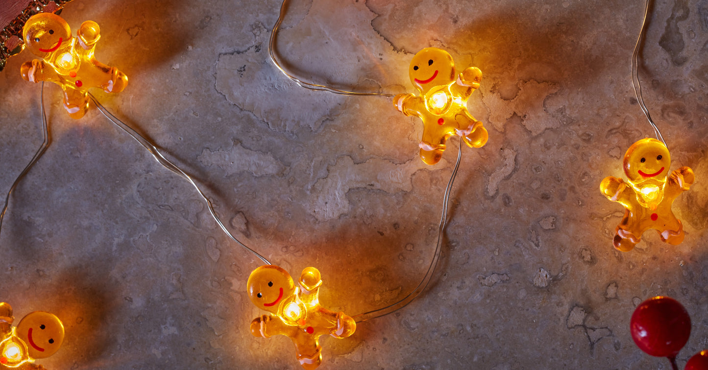 String of glowing gingerbread man lights on a textured surface