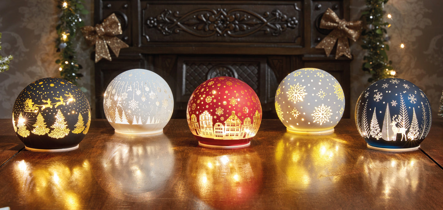 Set of five decorative glass lights with winter scenes on a wooden surface.