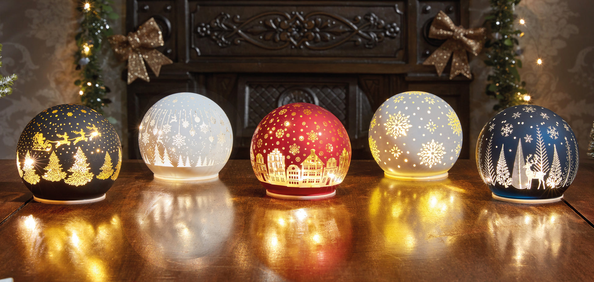 Set of five decorative glass lights with winter scenes on a wooden surface.