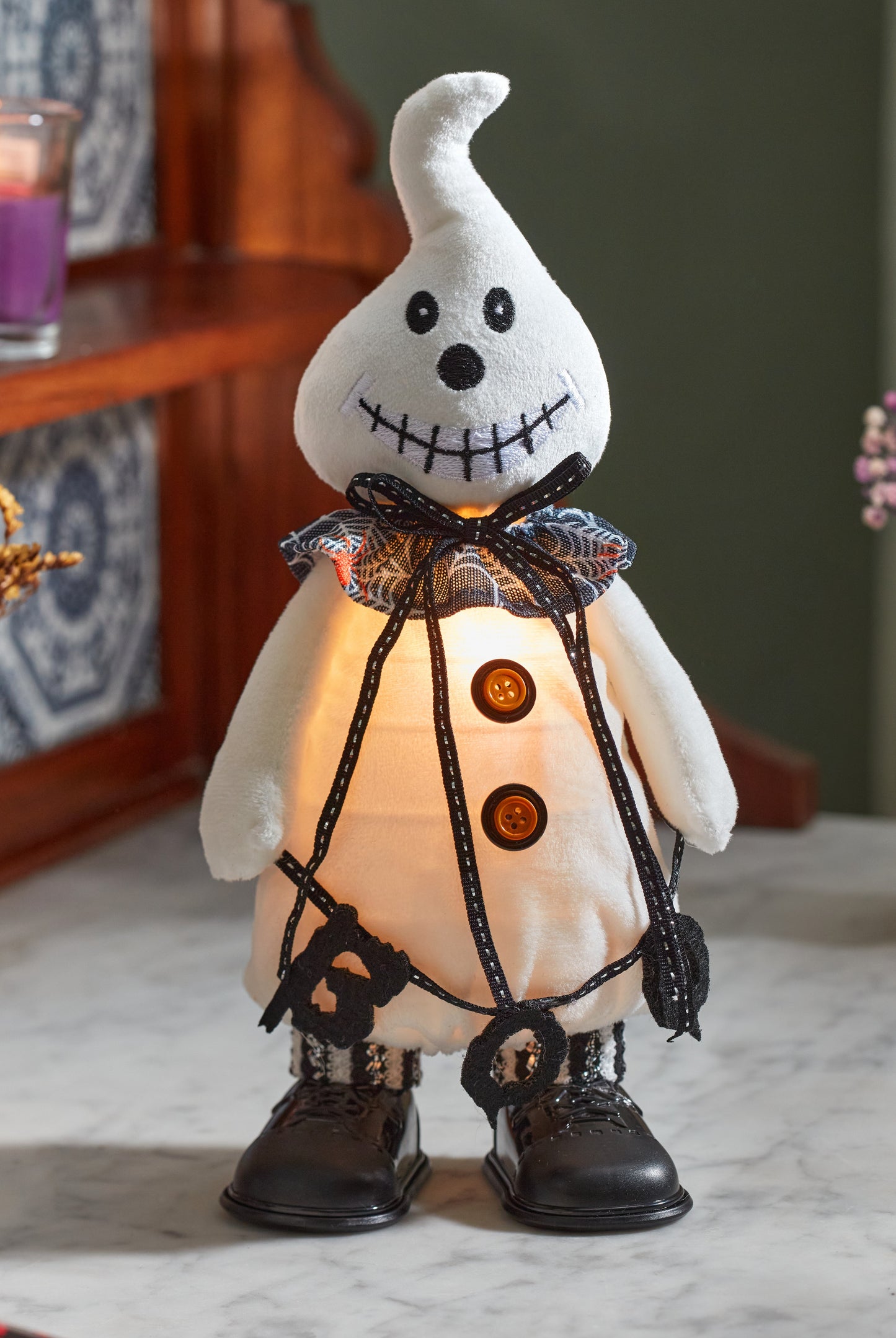 Halloween-themed ghost decoration with a light inside on a marble surface.