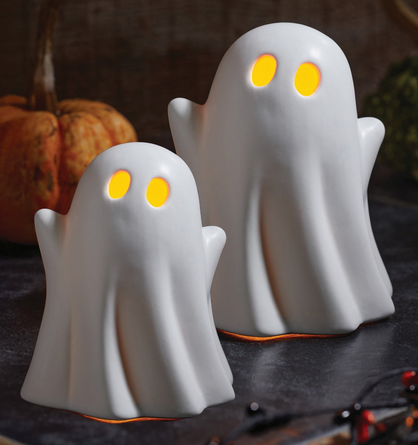 Two ghost-shaped lights with glowing eyes on a Halloween-themed background.
