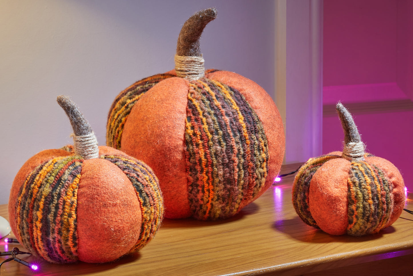 Decorative pumpkins with knitted patterns on a wooden surface.