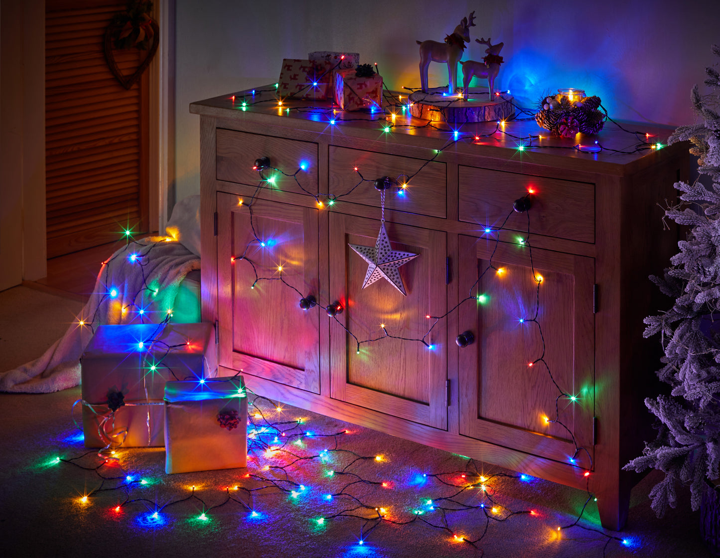 Wooden cabinet decorated with colorful string lights and Christmas decorations in a cozy room.