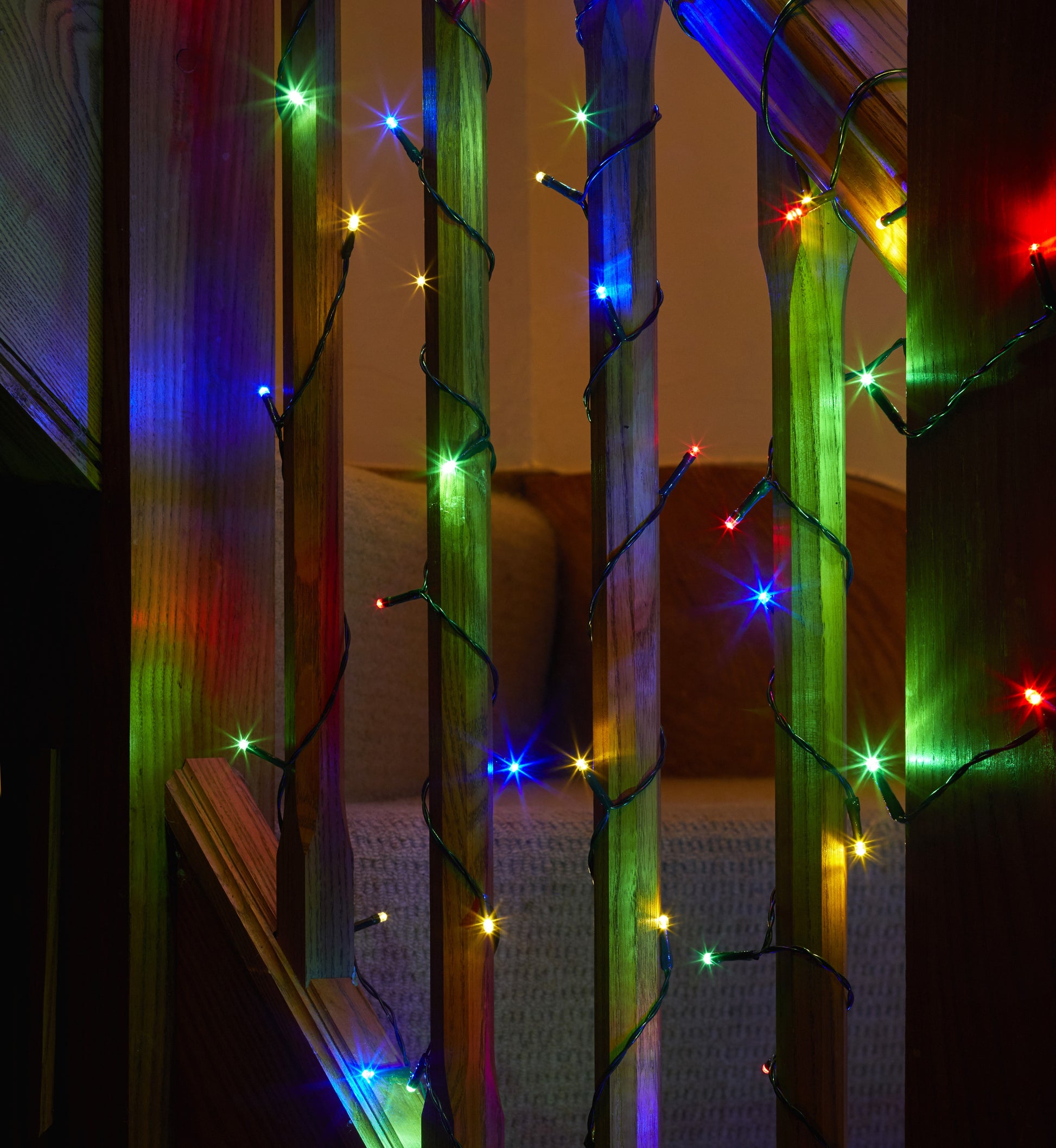 Colorful string lights on a wooden staircase with a neutral background