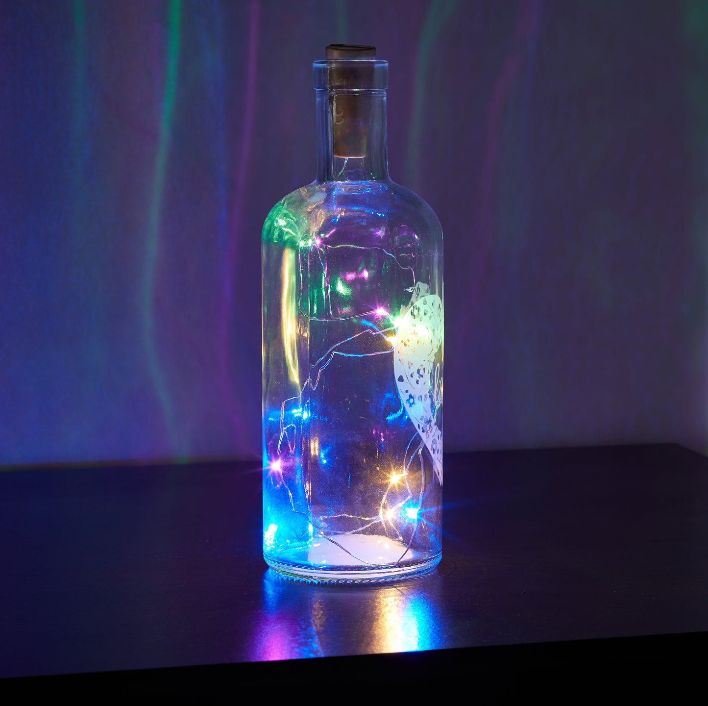 Decorative glass bottle with colorful lights against a dark background