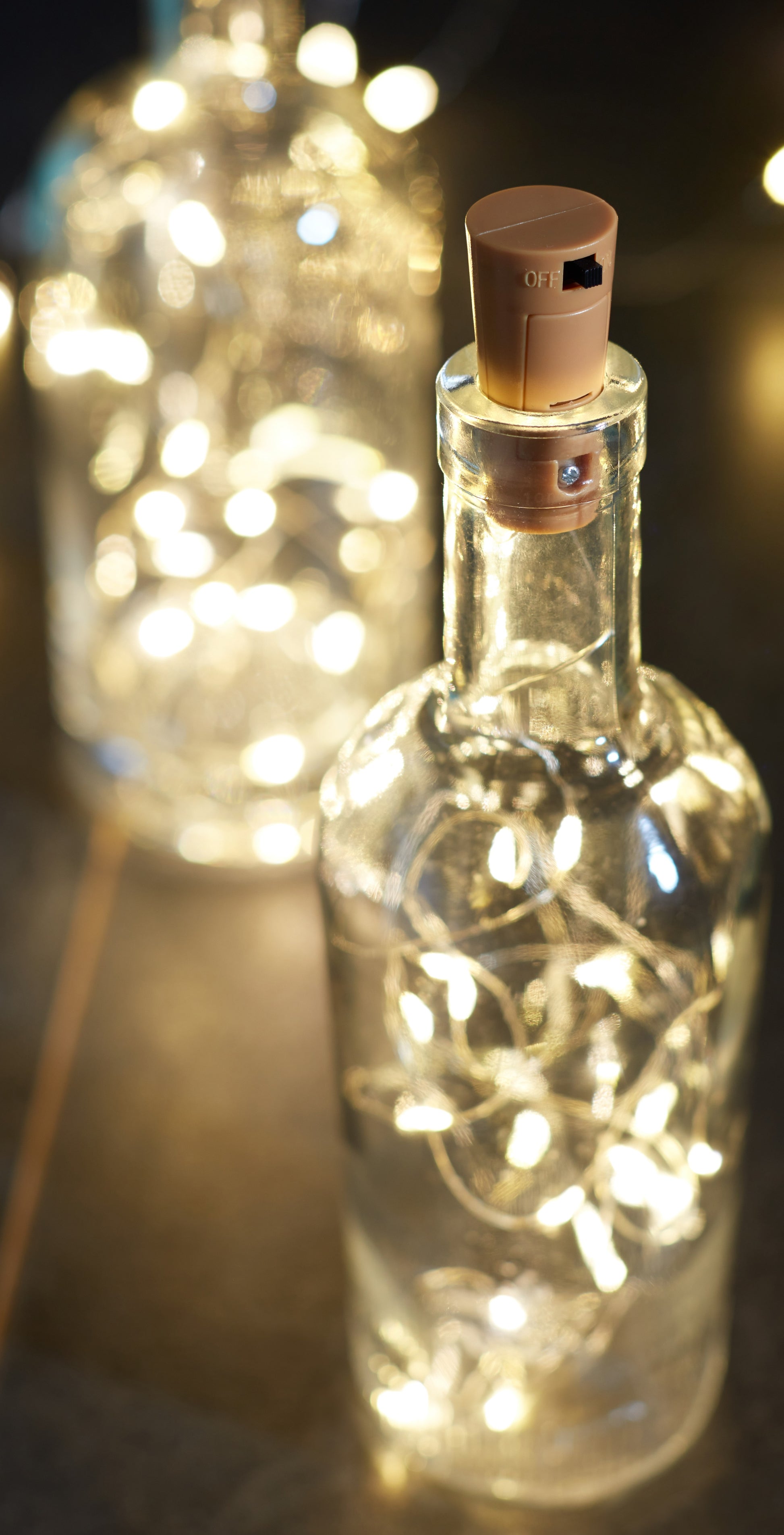Decorative glass bottle with fairy lights inside, cork stopper, on a blurred background