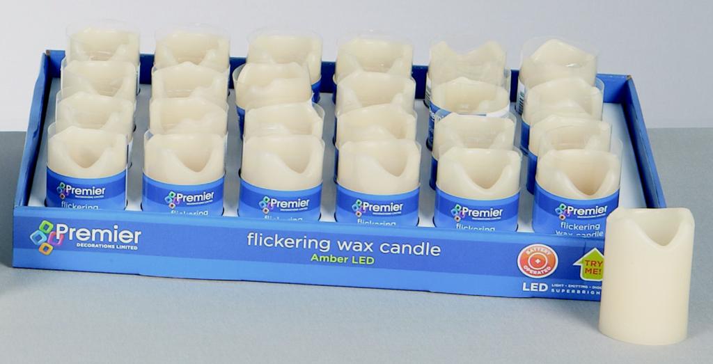 Box of Premier flickering wax candles with one candle outside the box on a gray surface.