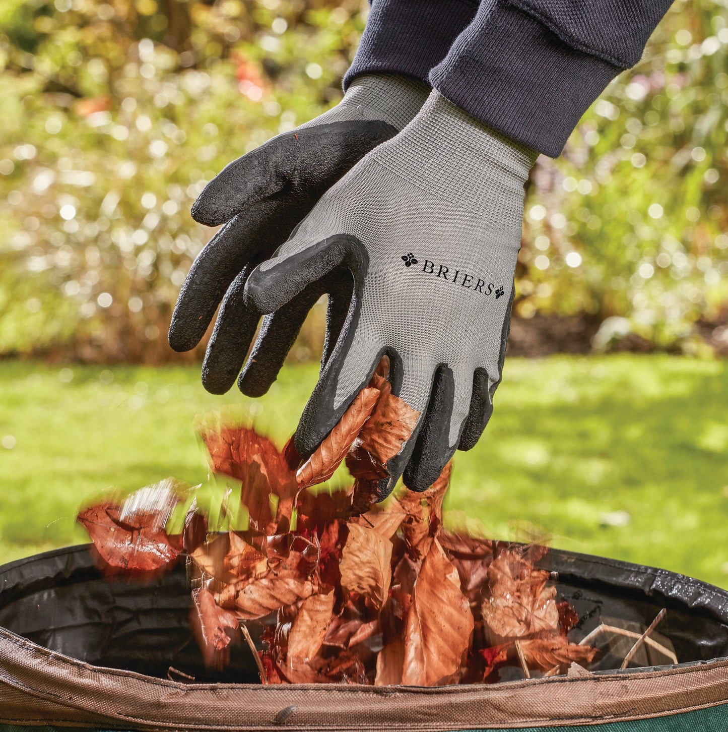 Person wearing Briers gardening gloves handling leaves in a garden setting
