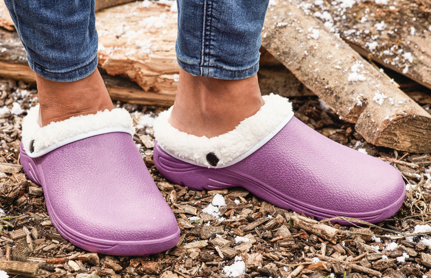 Purple clogs with white fur lining worn on a wooden floor