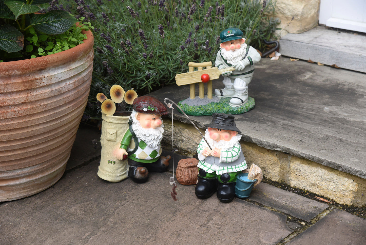 Gnome figurines in a garden setting with plants and a pot.