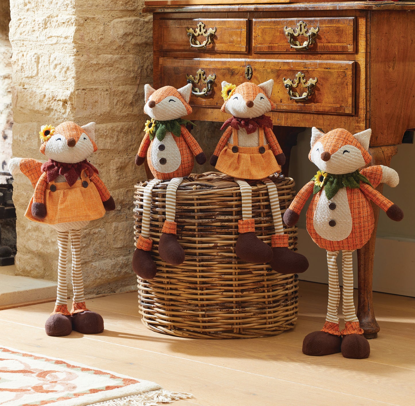 Four fox-shaped decorative items in front of a wooden dresser.