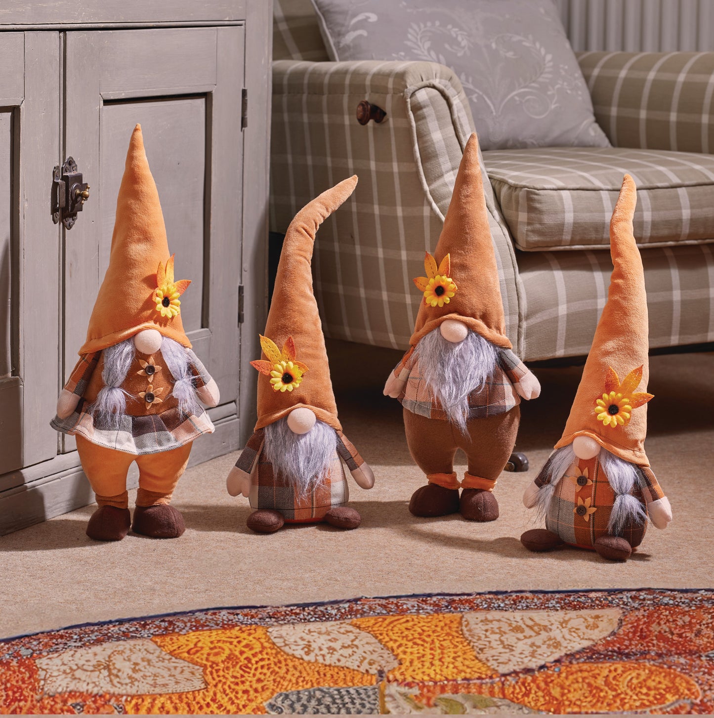 Four decorative gnomes with sunflower hats on a carpeted floor.