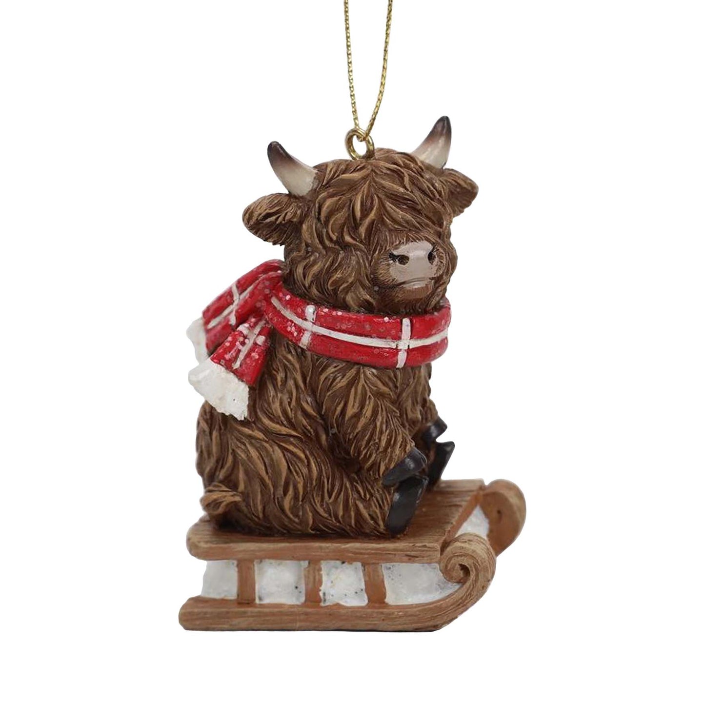 Brown Highland cow calf ornament sitting on a small wooden sleigh wearing a red and white plaid scarf.