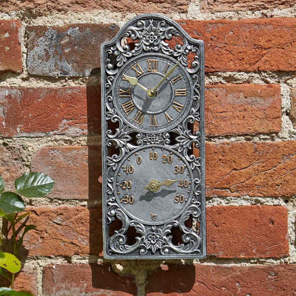 Decorative wall clock with thermometer on a brick wall