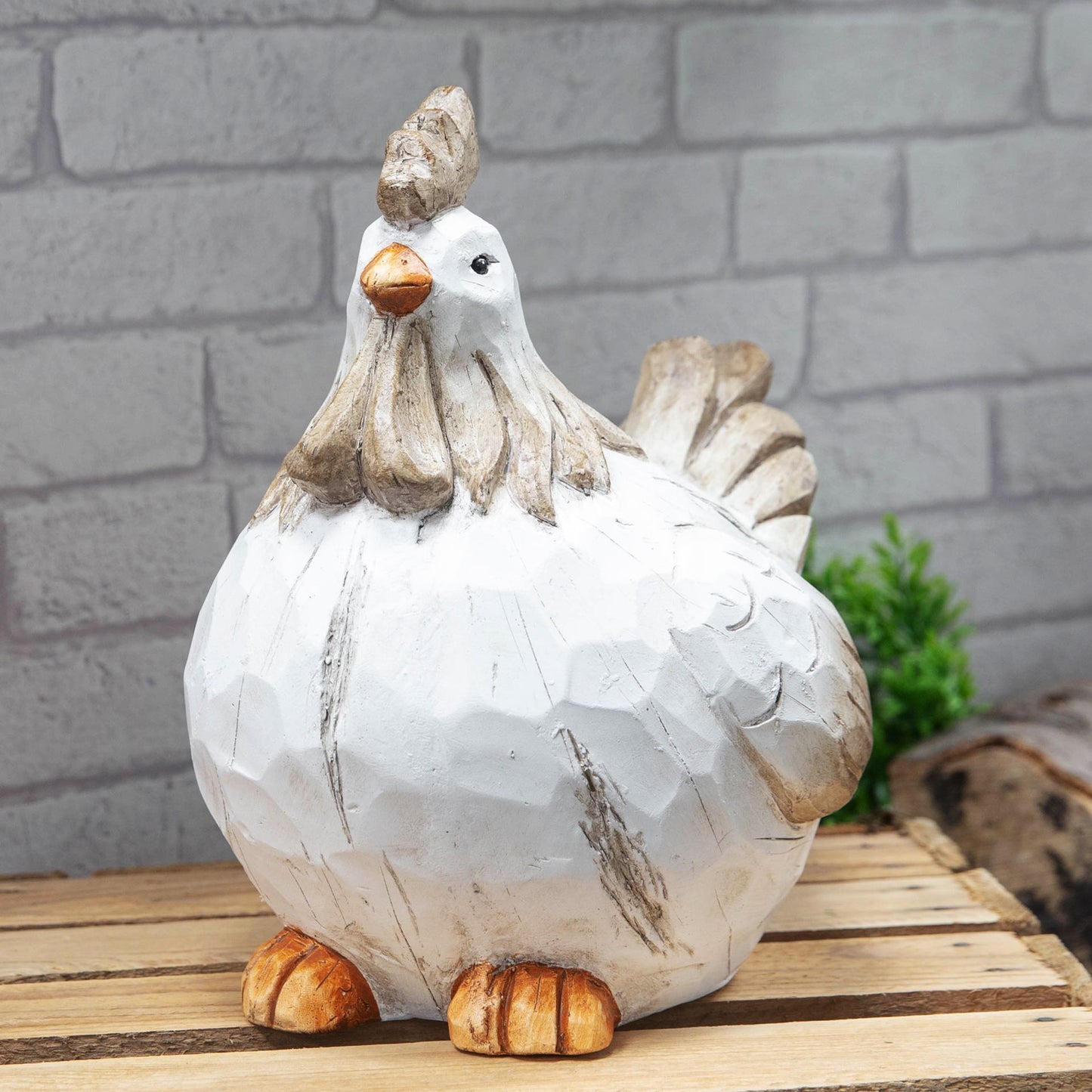 Decorative chicken figurine on a wooden surface with a brick wall background