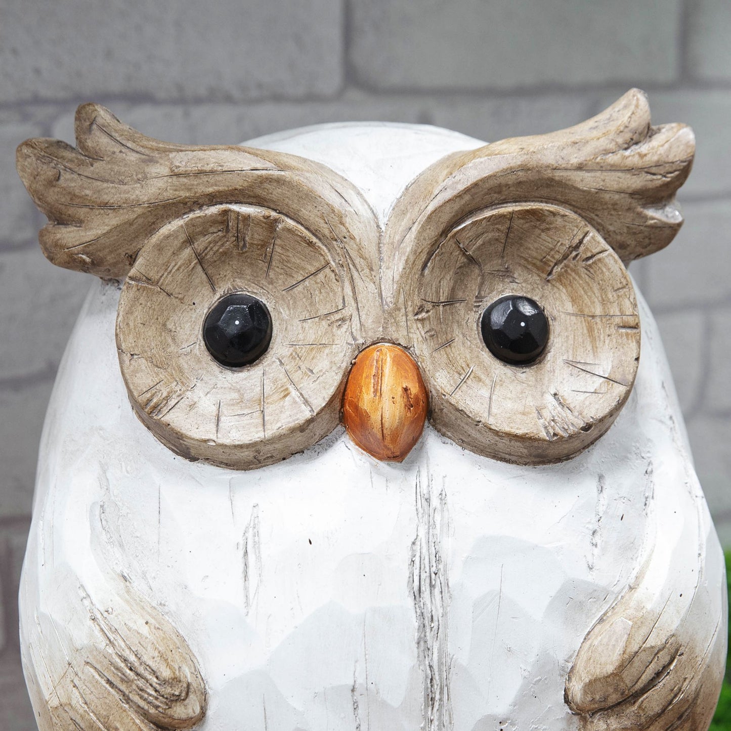 Wooden owl figurine with a gray brick background