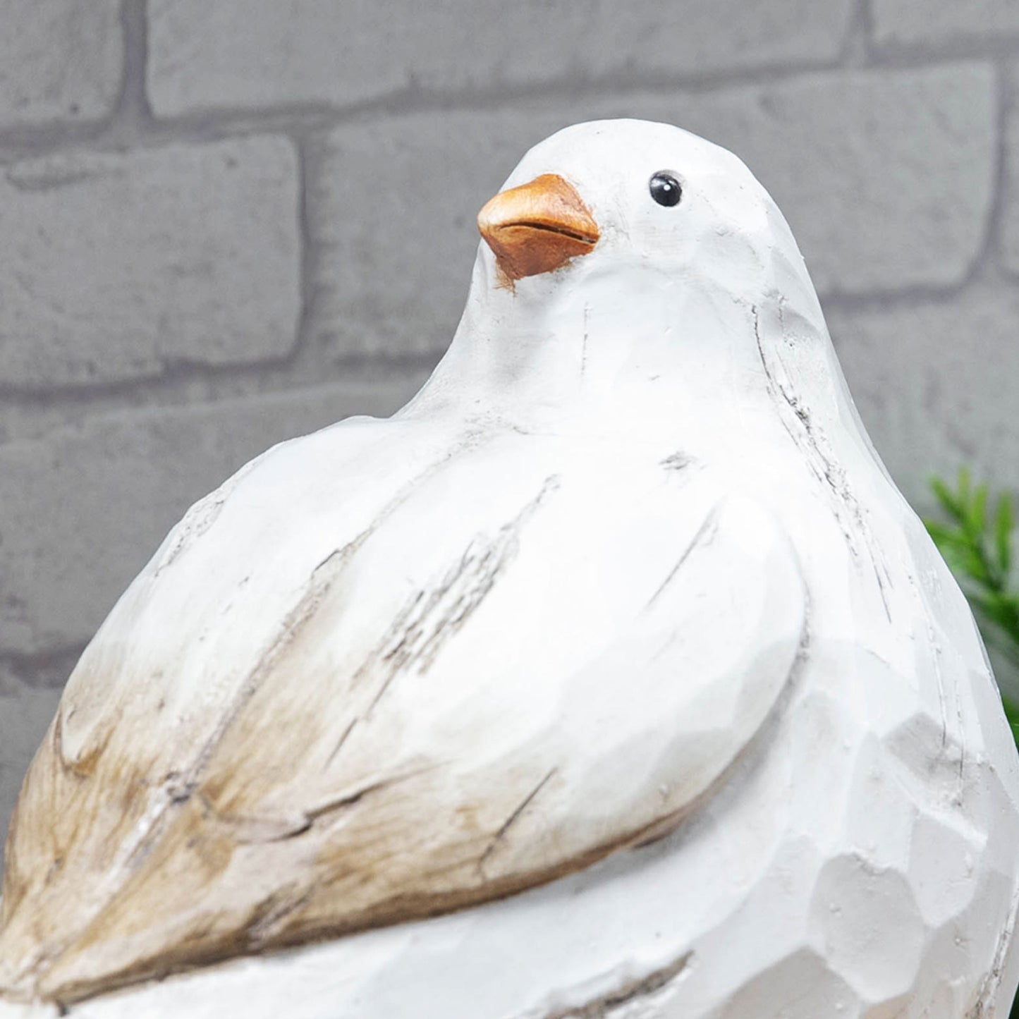 Decorative white bird sculpture with a brick wall background