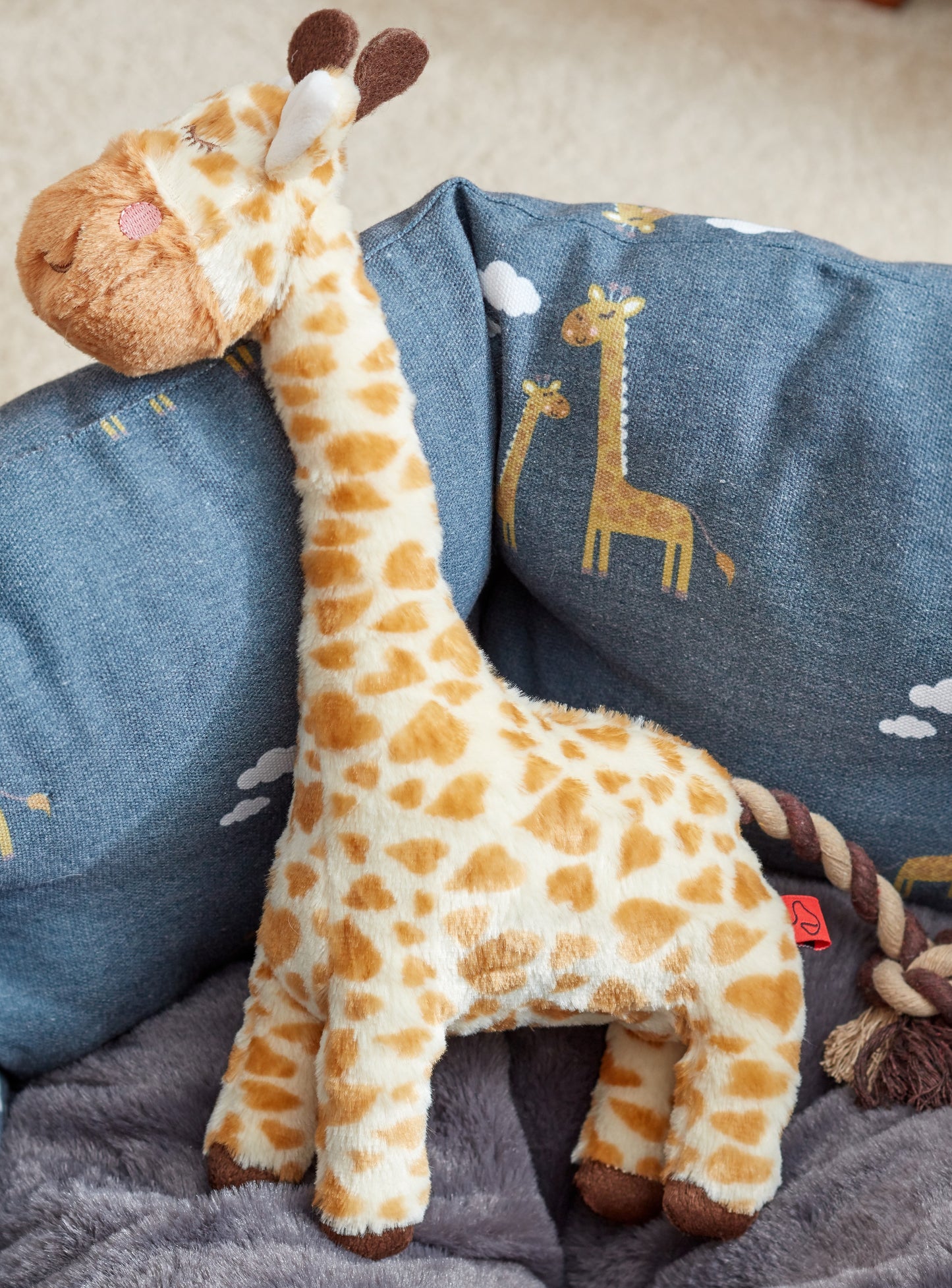 Plush giraffe toy on a blue blanket with giraffe designs