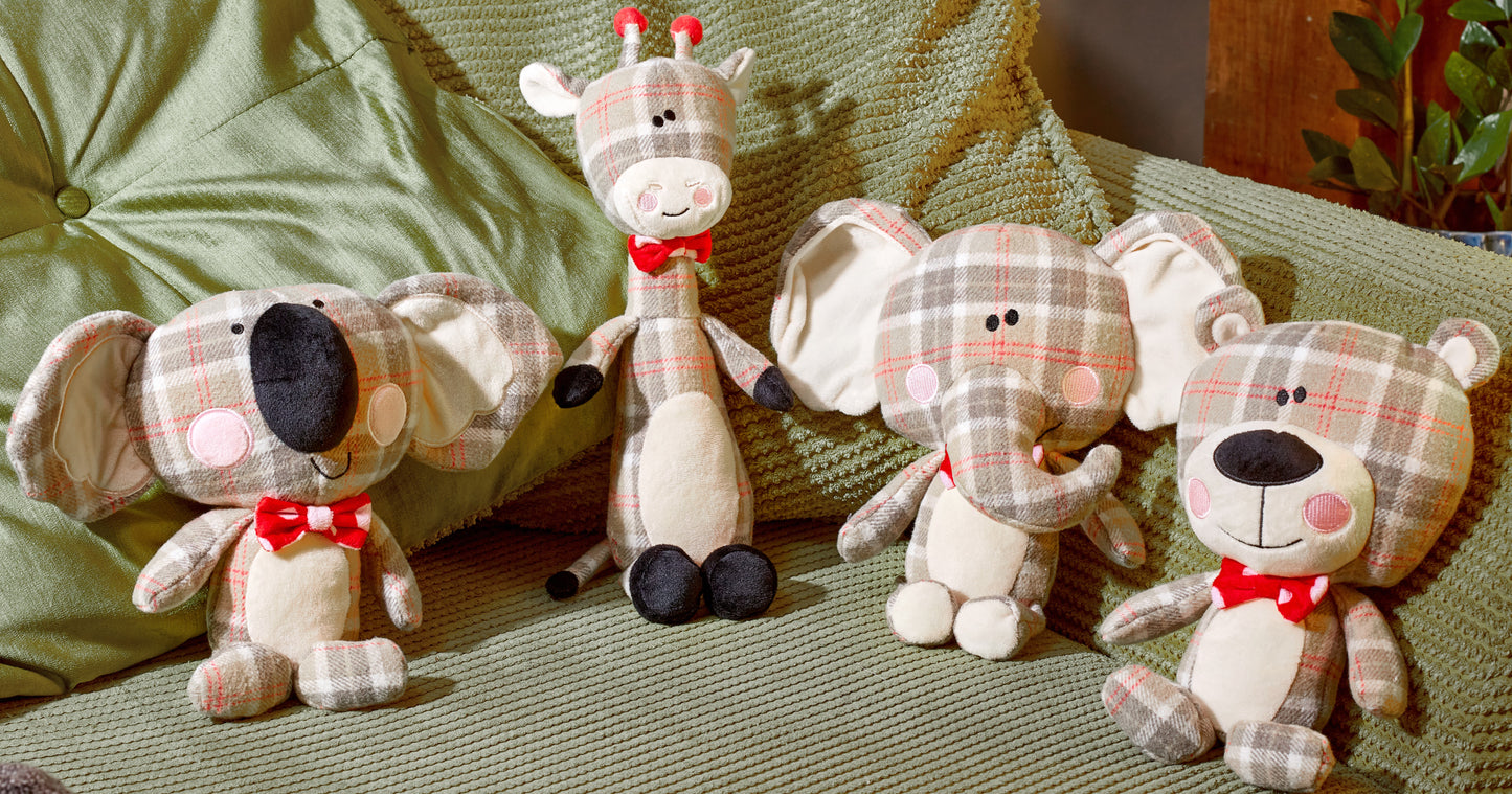Four plush toys, including a giraffe and elephants, on a textured surface.