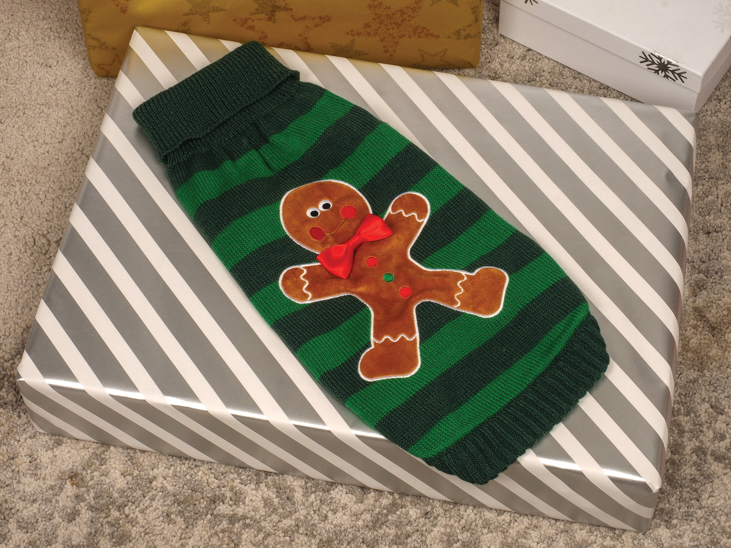 Green and black striped sweater with gingerbread man design on a striped box.