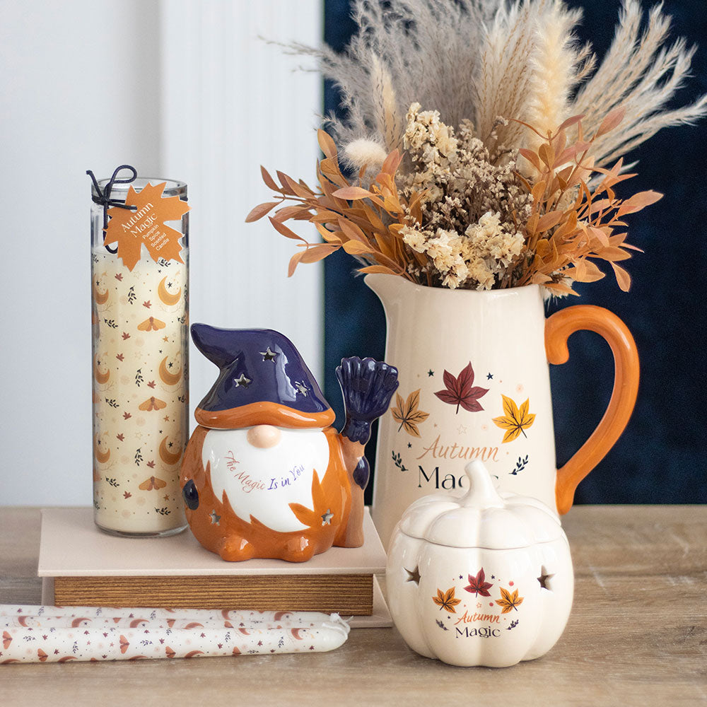 Autumn-themed decorative items including a gnome, pitcher, and pumpkin on a wooden surface.