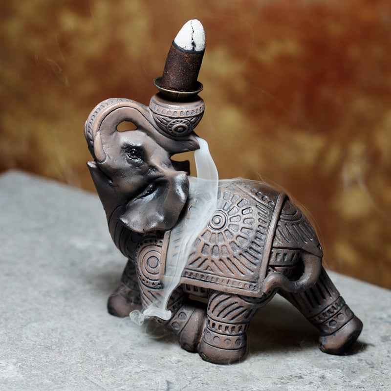 Decorative elephant incense burner with intricate designs on a neutral background