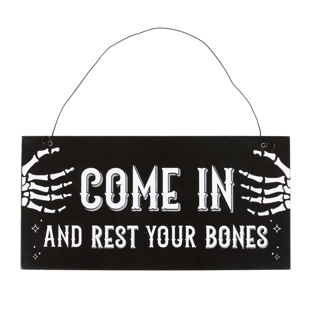 Hanging sign with skeleton hands and text 'Come in and rest your bones' on a black background