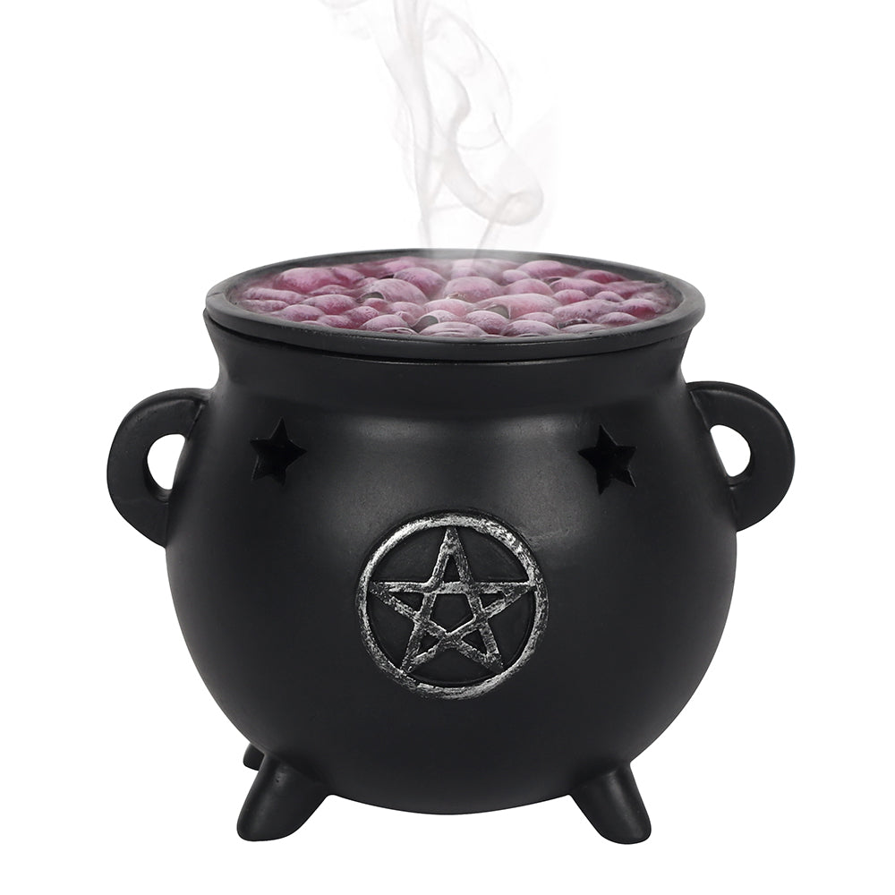 Black cauldron with a pentagram design containing pink incense balls on a white background