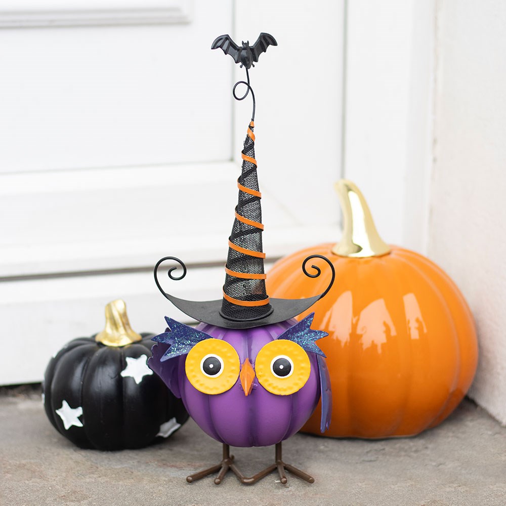 Halloween-themed decorative owl with a witch hat, surrounded by pumpkins on a neutral background