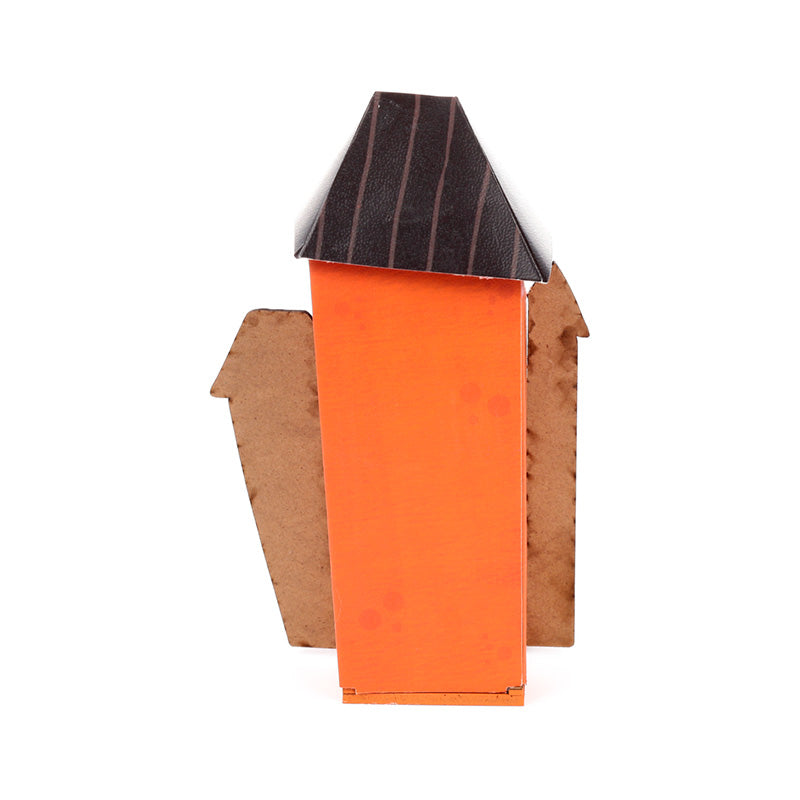 A handmade cardboard house model with a bright orange front wall, a dark brown slatted roof, and brown corrugated cardboard side walls, shown against a plain white background.
