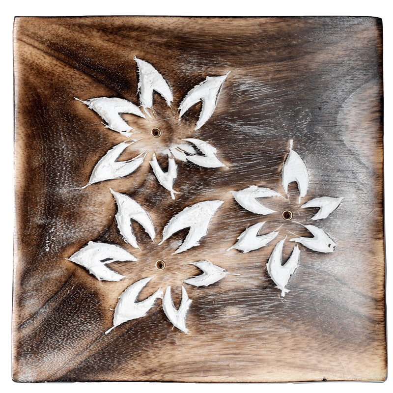 Wooden panel with white floral cutouts on a wooden background
