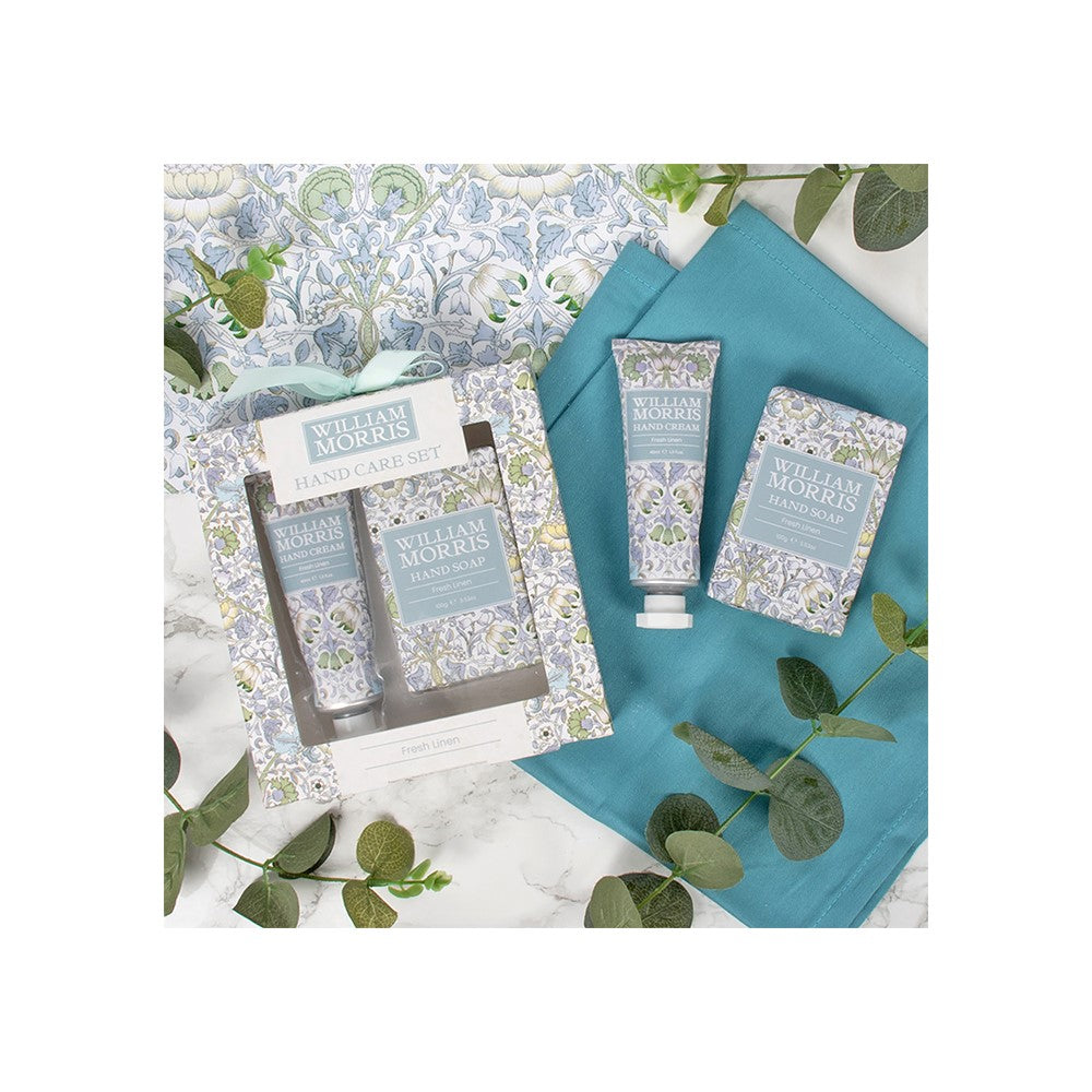 William Morris-themed toiletries including a soap, lotion, and towel on a floral background.