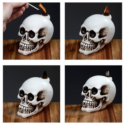 Skull-shaped candle holder with a match being lit and then left unlit on a wooden surface.
