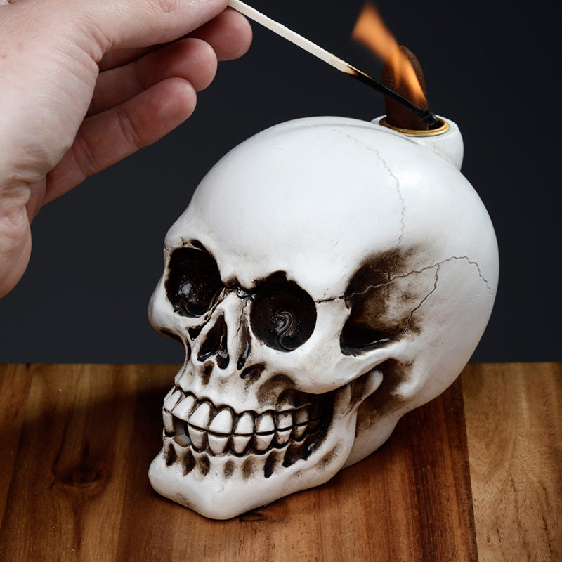 Skull-shaped candle being lit with a match on a wooden surface