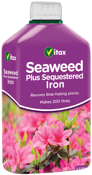 Vitax Seaweed Plus Sequestered Iron fertilizer bottle with flowers in the background