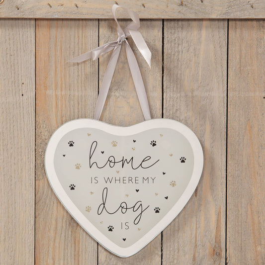 Heart-shaped sign with 'home is where my dog is' text on a wooden background