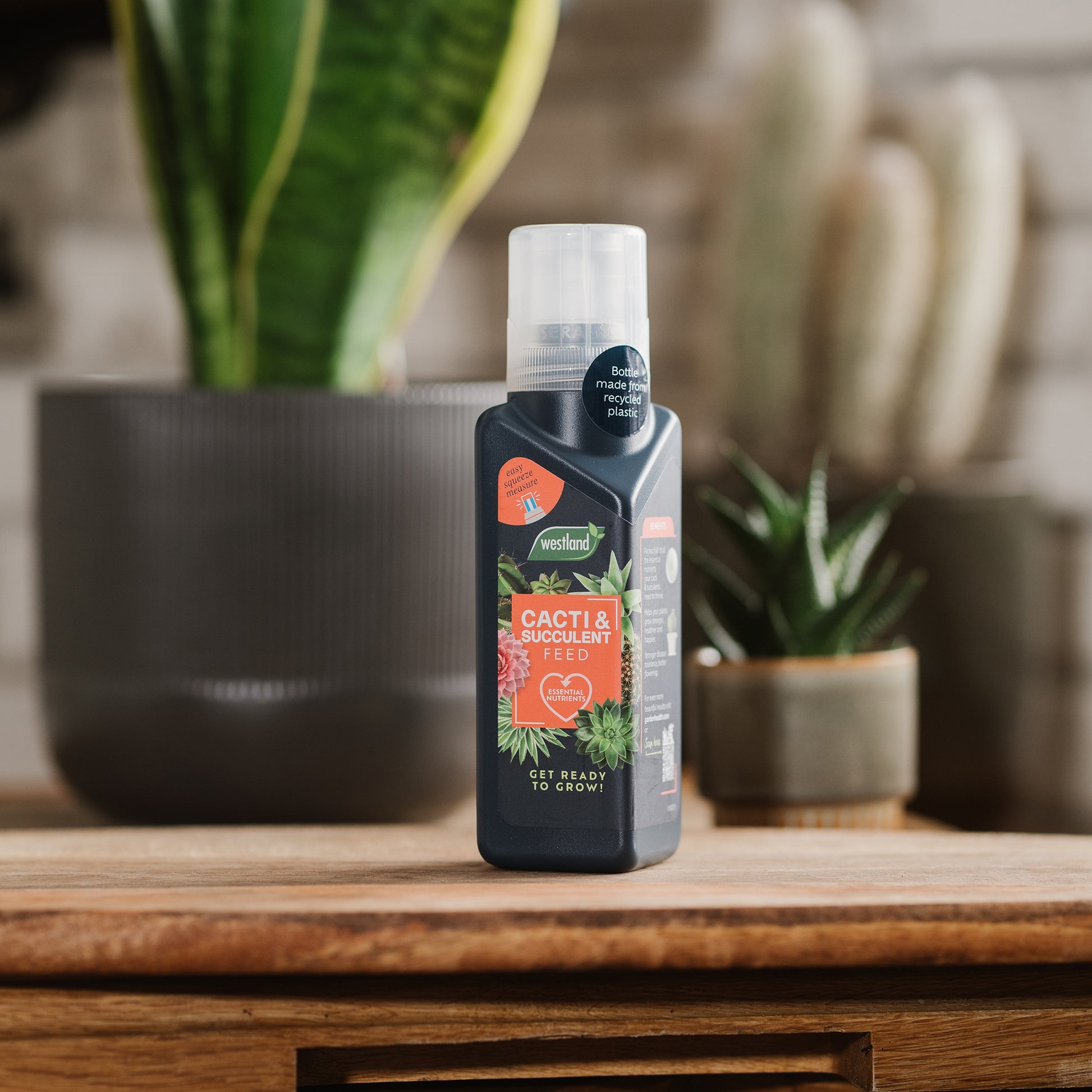 Bottle of plant care product on a wooden surface with plants in the background