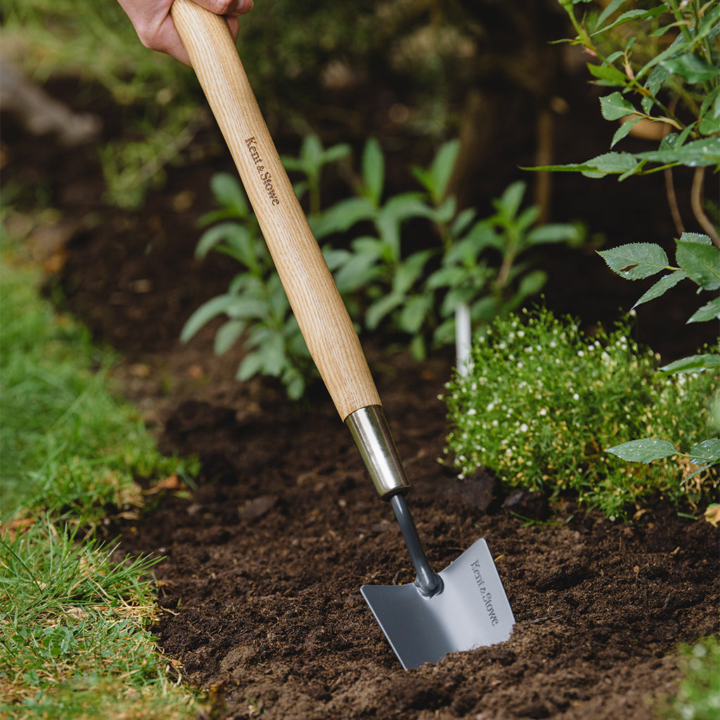 Kent & Stowe Carbon Steel Border Hand Trowel digging soil in a garden bed