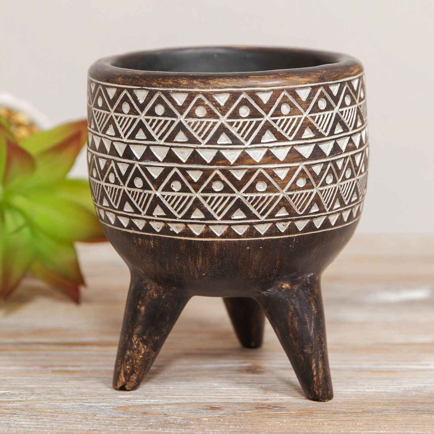 Decorative black pot with white geometric pattern on a wooden surface