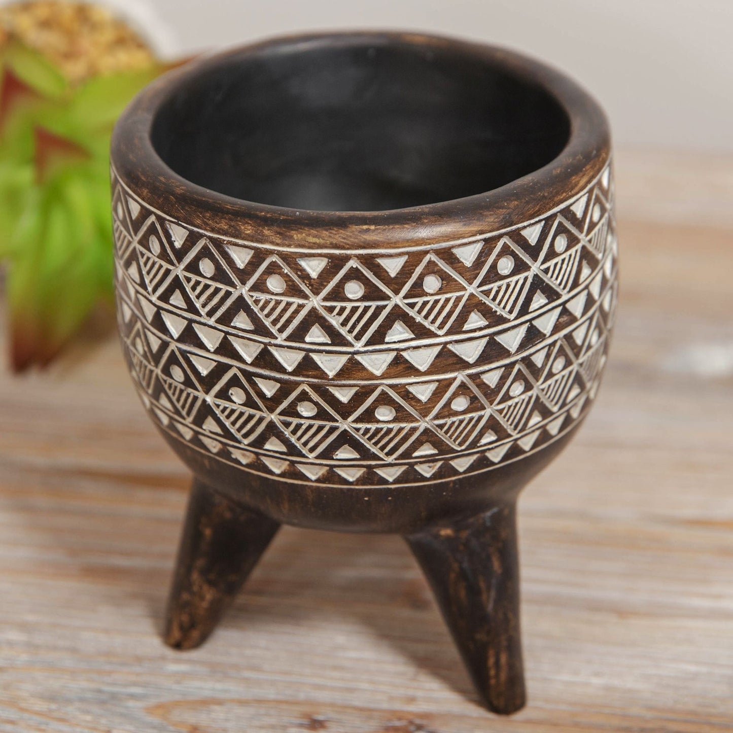 Ceramic pot with tribal patterns on a wooden surface