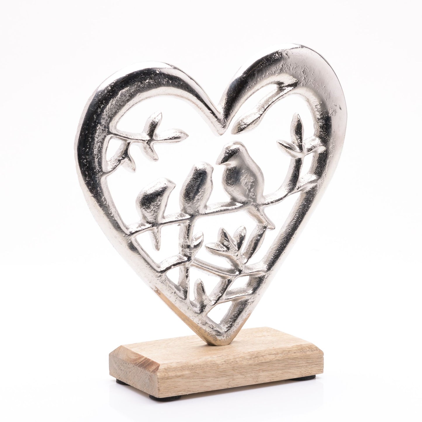 Silver heart-shaped sculpture with cut-out figures on a wooden base against a white background