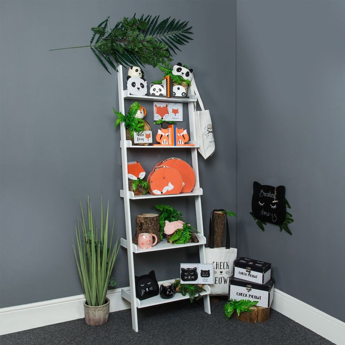 White ladder shelf against a gray wall with decorative items and plants.