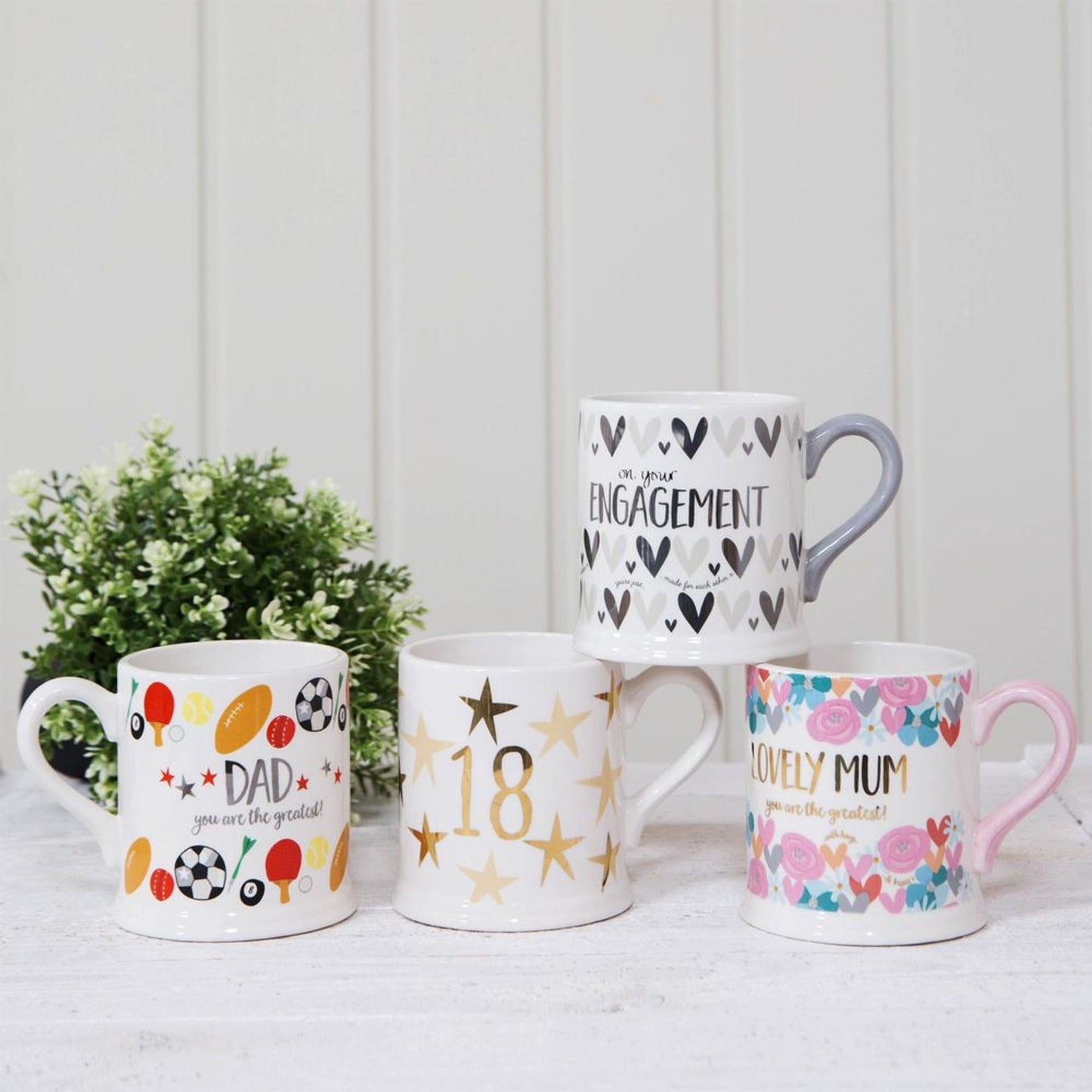 Four decorative mugs with various designs and text on a white surface.