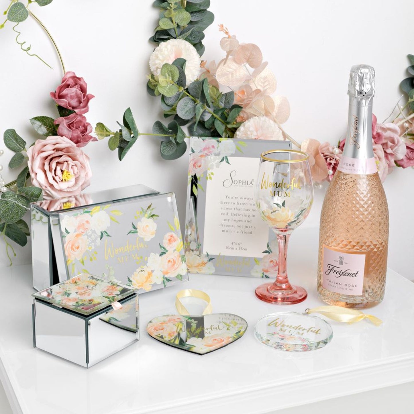 Bottle of Freixenet pink sparkling wine with decorative items on a white surface.