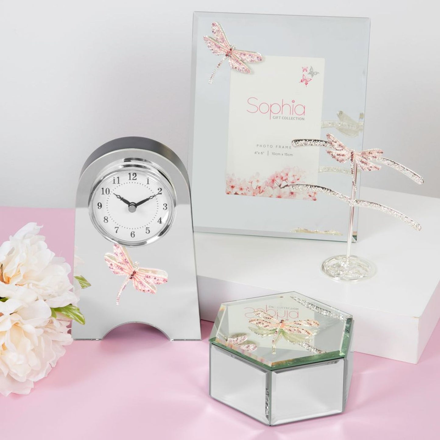 Decorative clock, card, and jewelry box with butterfly designs on a pink surface