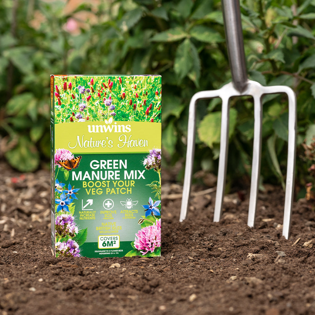 Unwins Green Manure Mix packaging on garden soil with a fork in the background