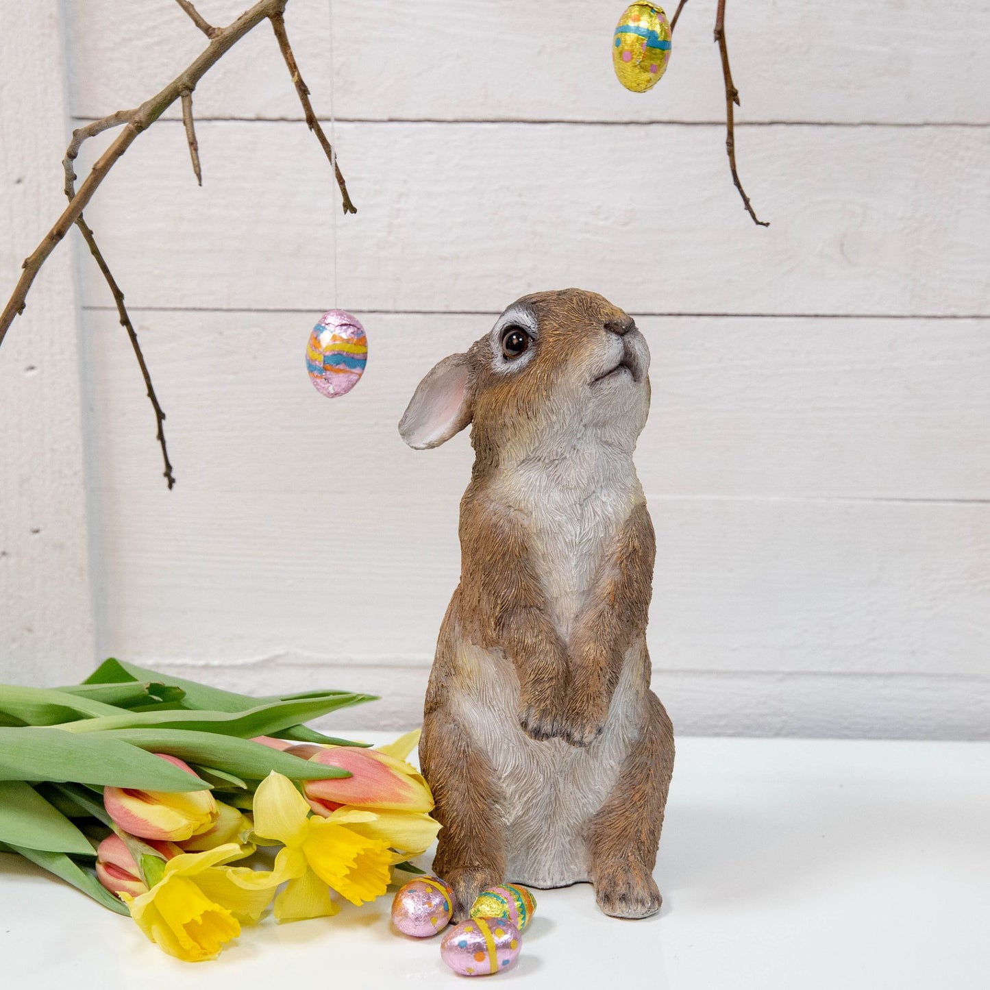 Stylized Easter scene with a rabbit, tulips, and Easter eggs on a white background