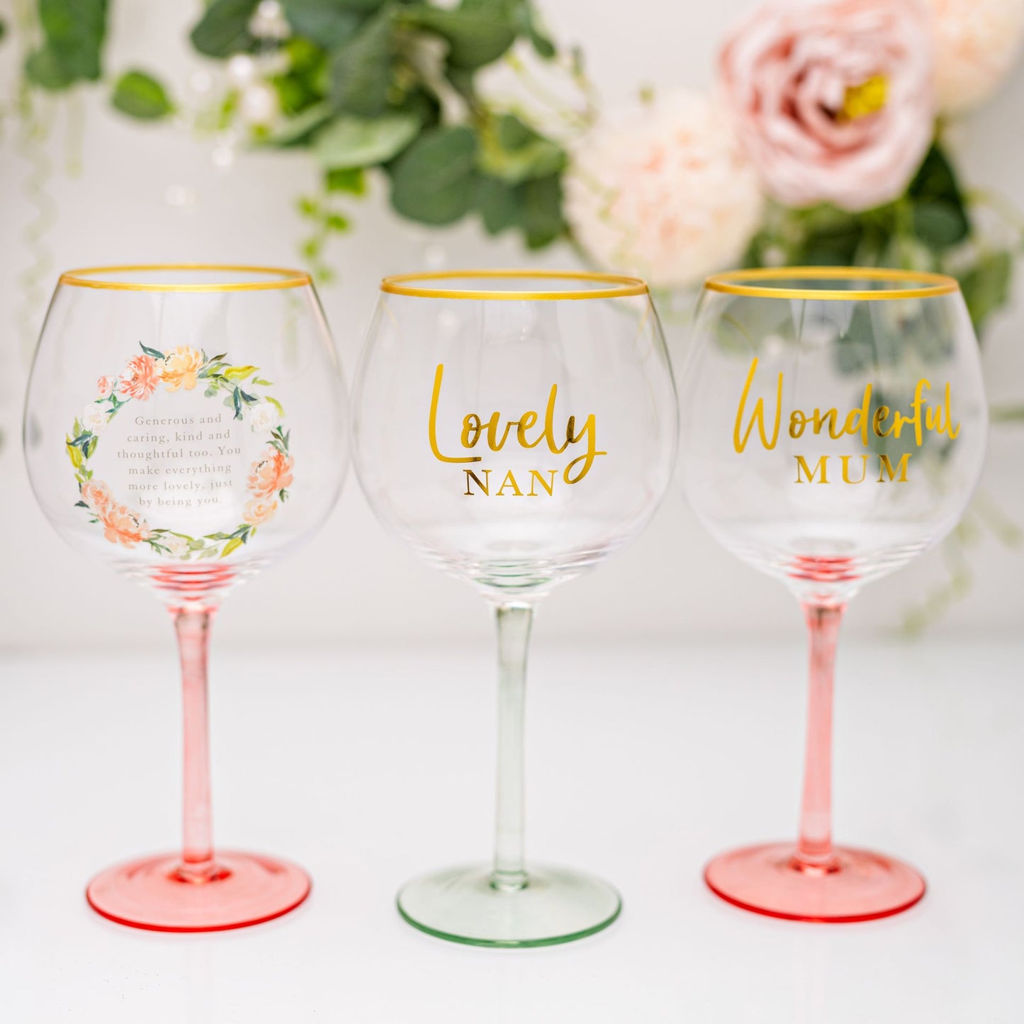 Three wine glasses with personalized inscriptions on a floral background