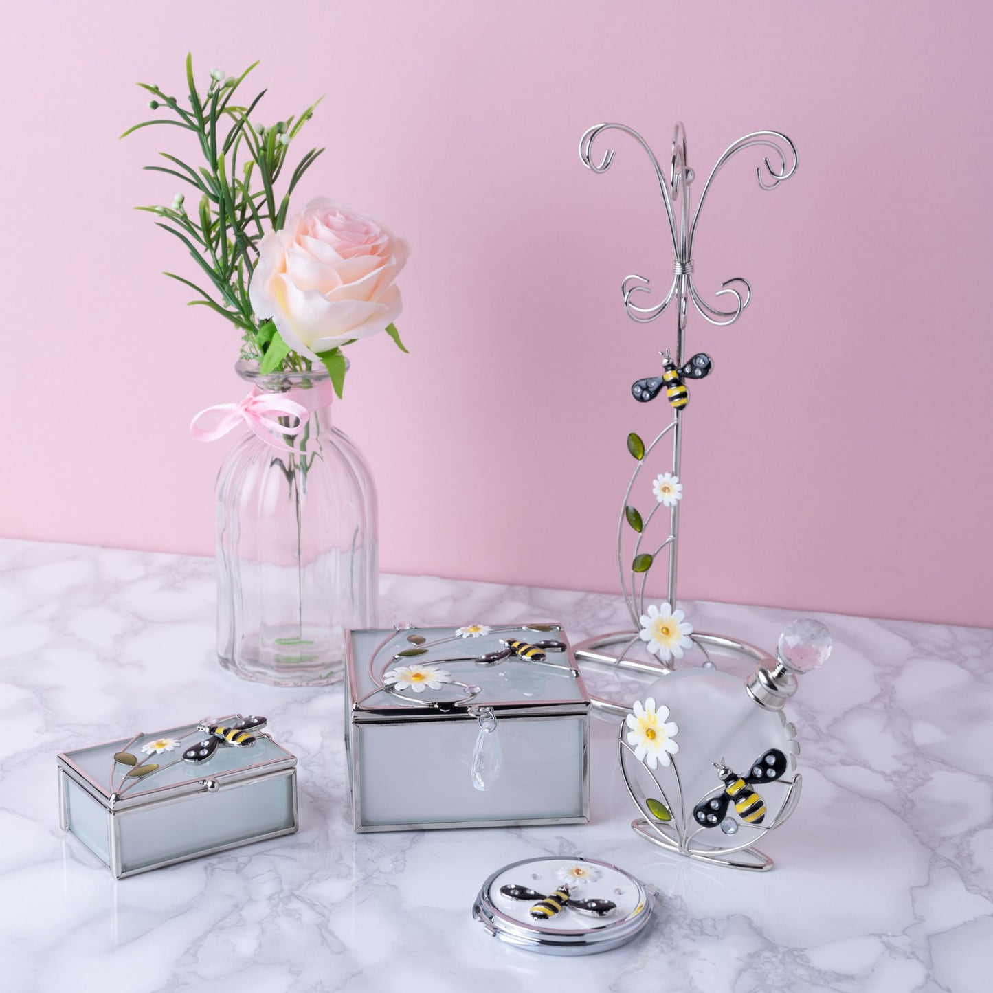 Decorative items including a jewelry stand, boxes, and a vase with flowers on a marble surface.